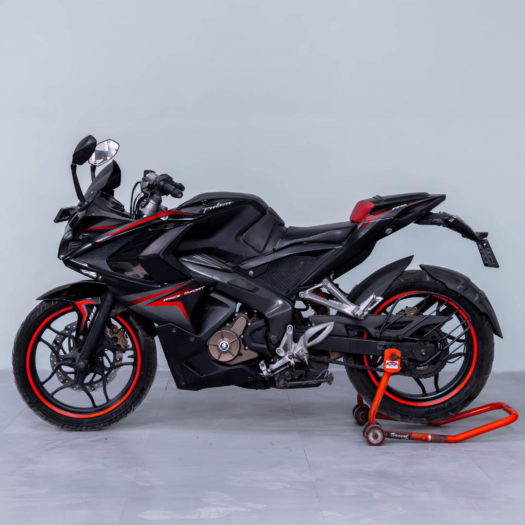 Bajaj Pulsar RS 200 black sports bike with red accents on a paddock stand, side profile view.