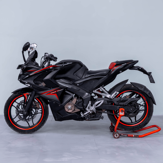 Bajaj Pulsar RS 200 black sports bike with red accents on a paddock stand, side profile view.