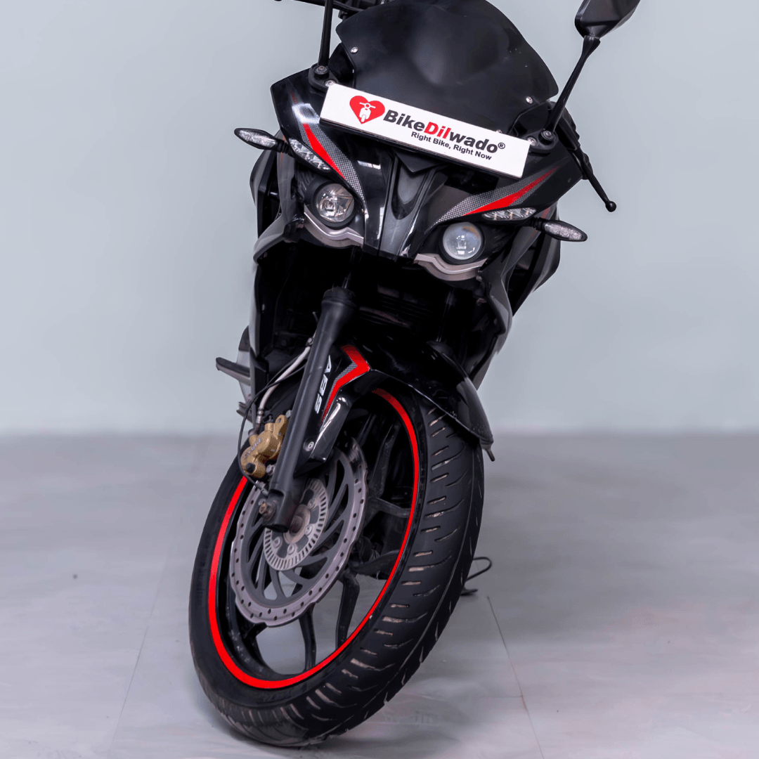 Front view of Bajaj Pulsar RS 200 with dual headlights and BikeDiWado branding on the windshield.
