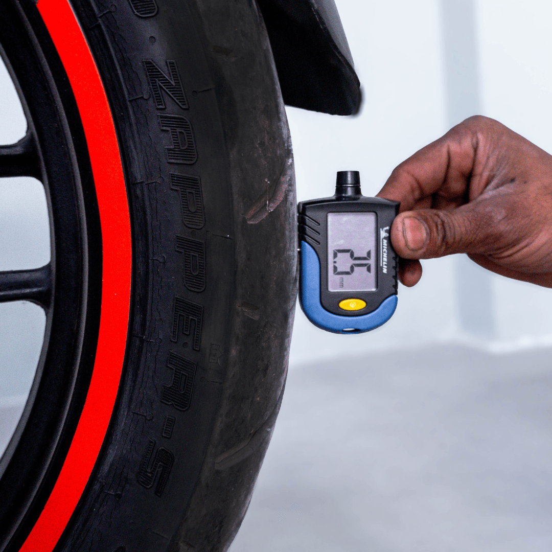 Digital gauge measuring tire tread depth on Bajaj Pulsar RS 200 rear wheel.