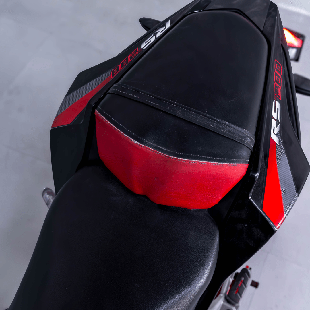 Close-up of Bajaj Pulsar RS 200 seat with red and black leather design and RS 200 branding.