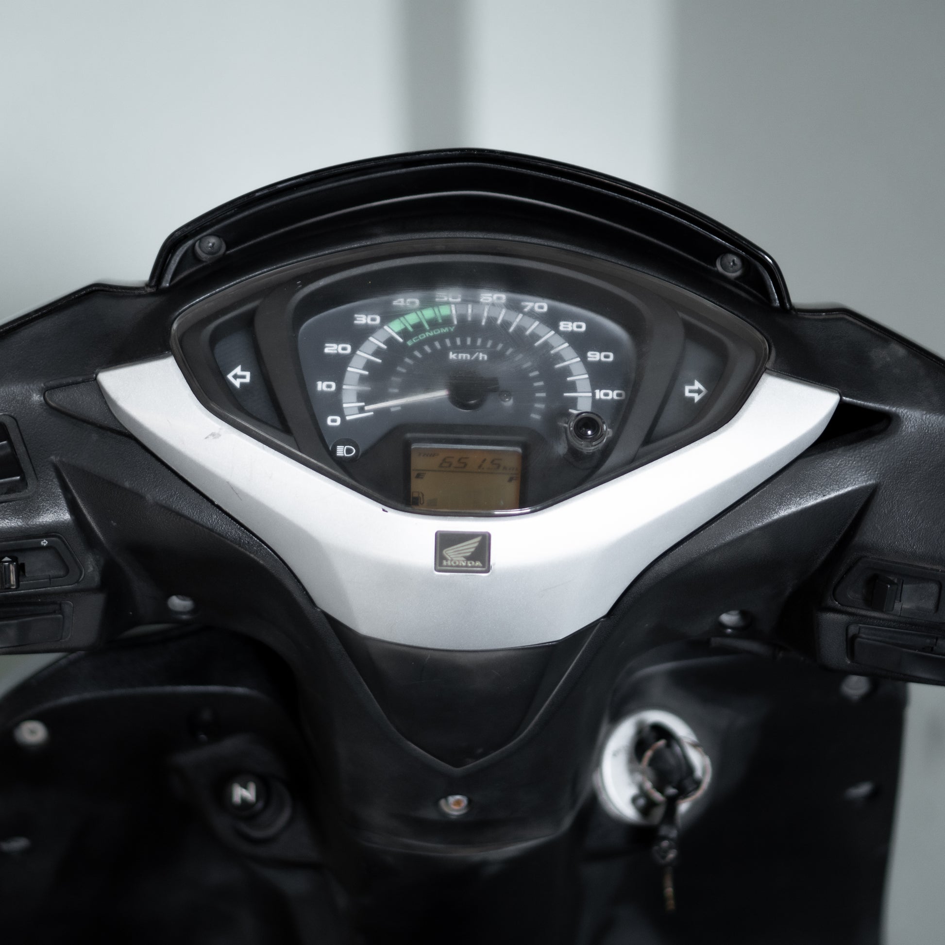 Close-up of a motorcycle dashboard with speedometer and tachometer on a blurred background