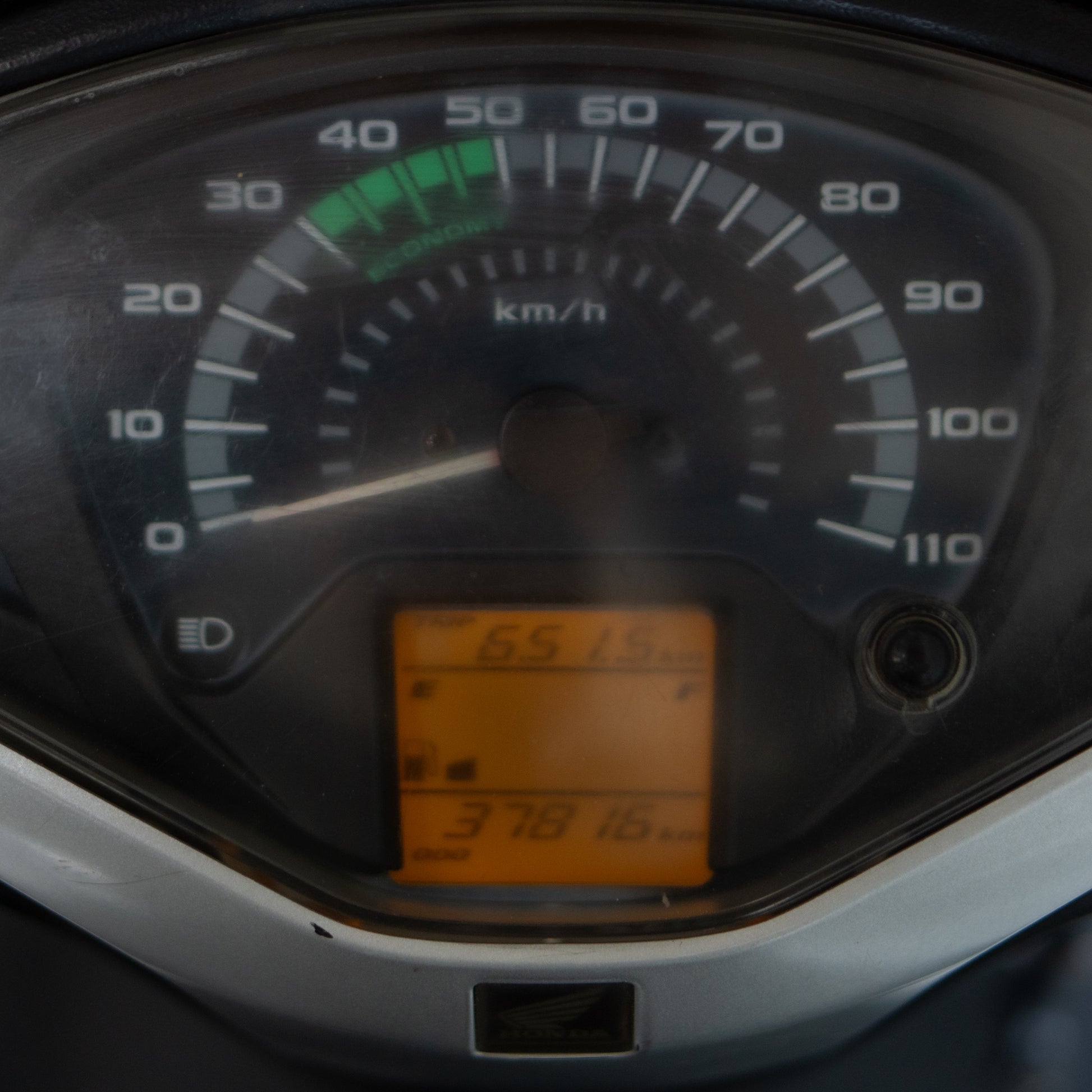 Close-up of a motorcycle speedometer with digital display showing speed and other metrics.