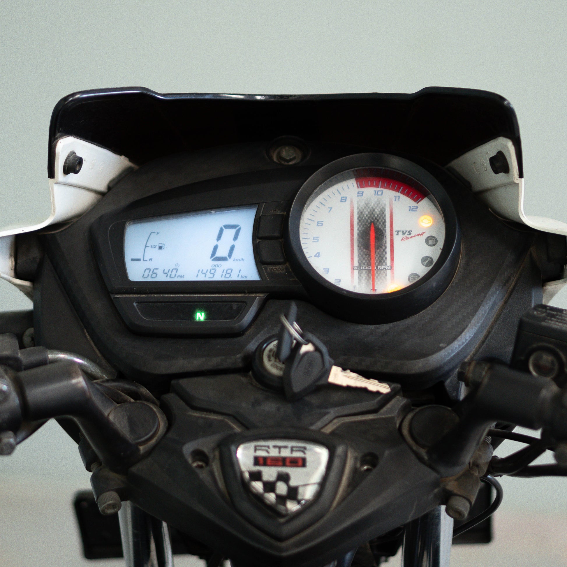 Close-up of a motorcycle dashboard with digital and analog gauges on a light gray background. TVS Apache RTR 160 4V Used Bike for Sale in Gurgaon