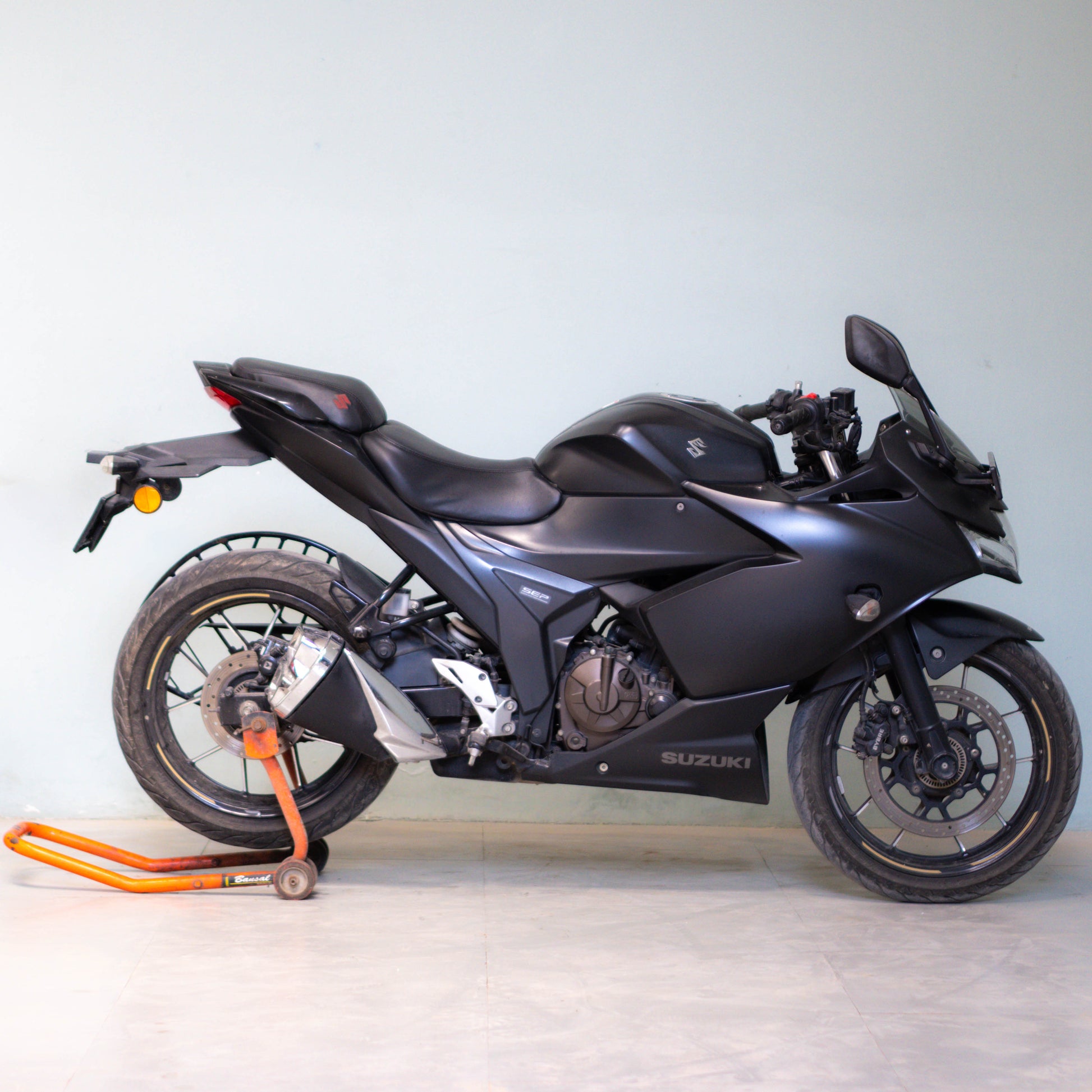 Black Suzuki motorcycle on a stand against a light gray background Gixxer SF 250 second hand price gurgaon
